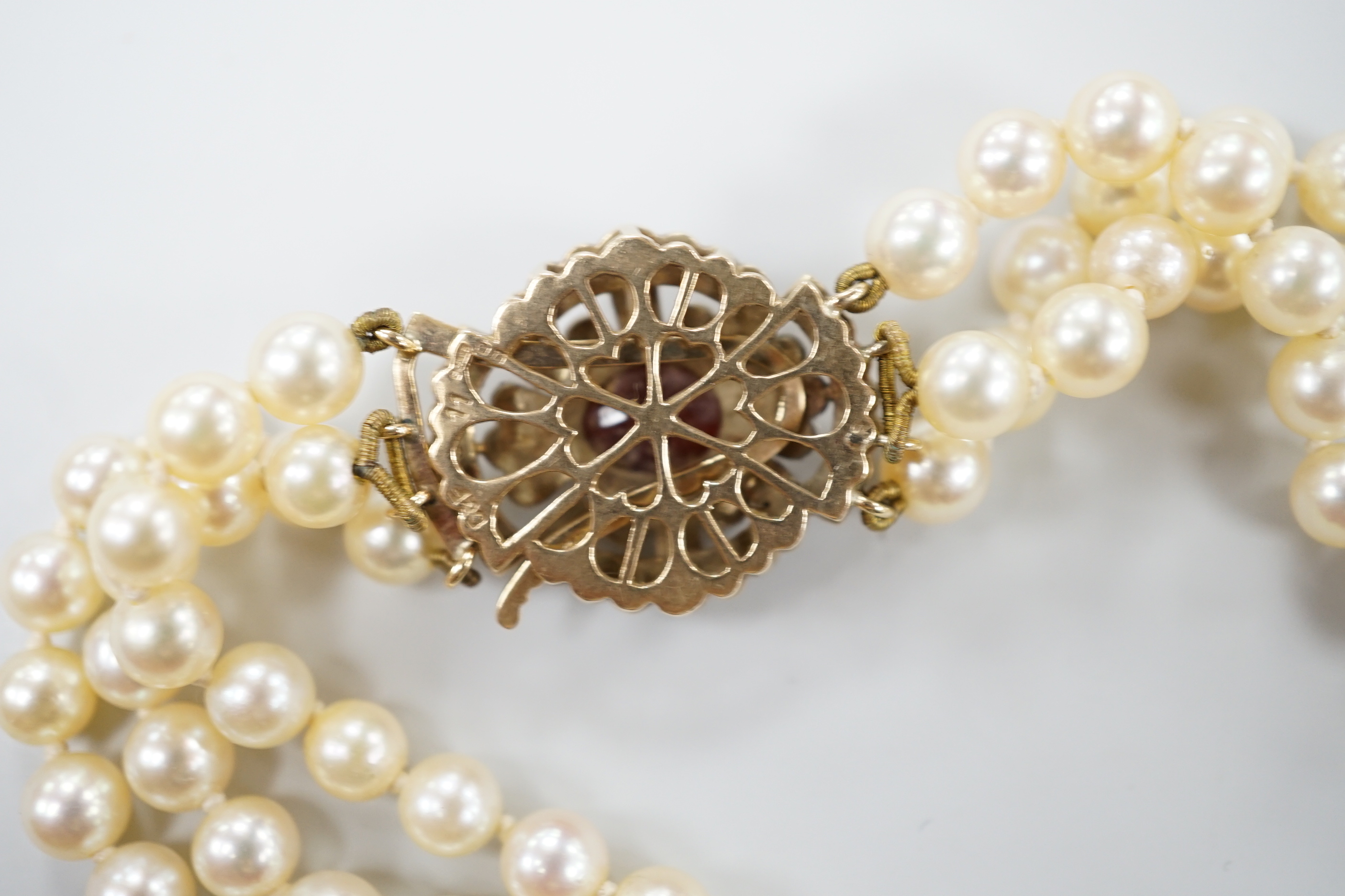 A 1960's triple strand cultured pearl choker necklace by Cropp & Farr, with 9ct gold, garnet and seed pearl set clasp, 39cm.